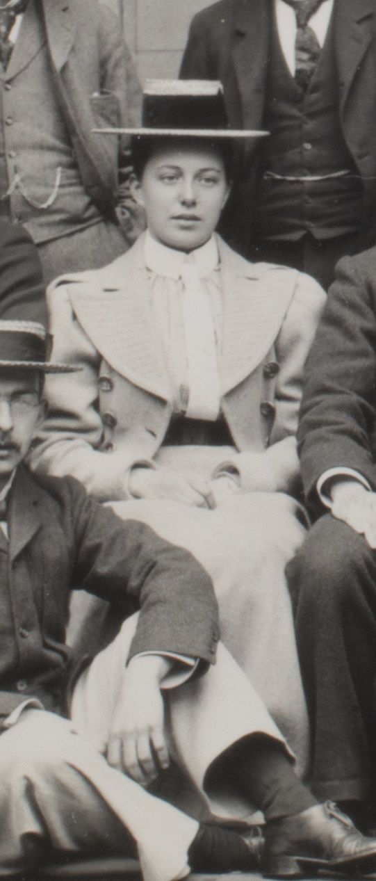 Formal photograph of woman seated outside. She is wearing a hat.